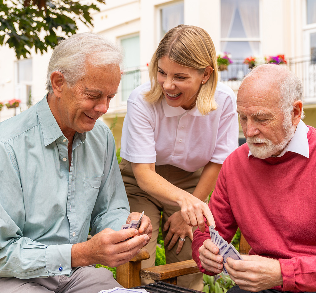 Two residents seated over a game of cards with team member