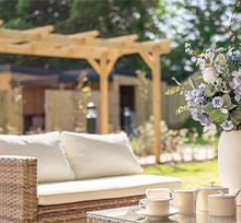 A cozy patio featuring wicker furniture surrounded by vibrant flowers in full bloom.