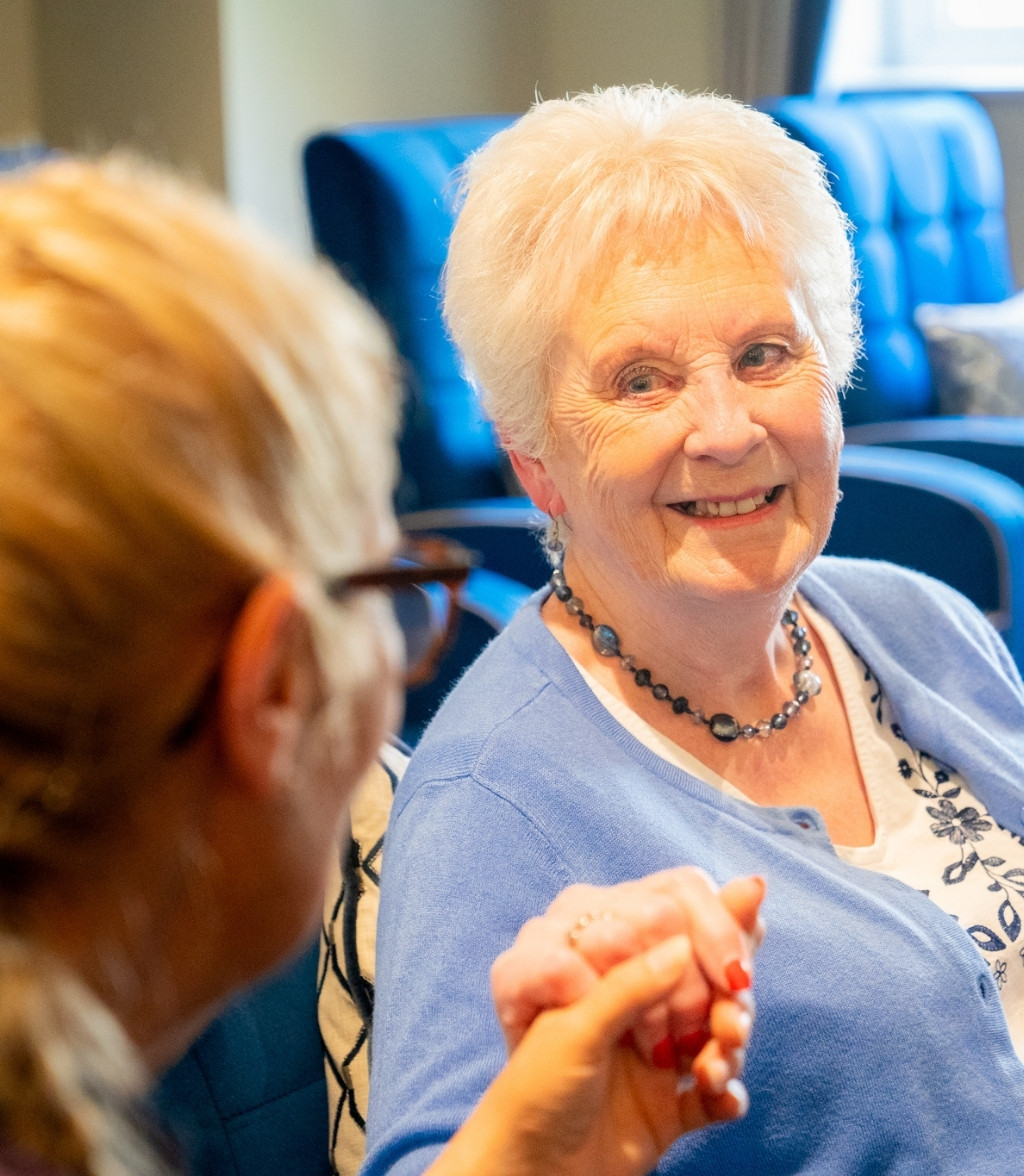 A resident engages in conversation with a carer both smiling