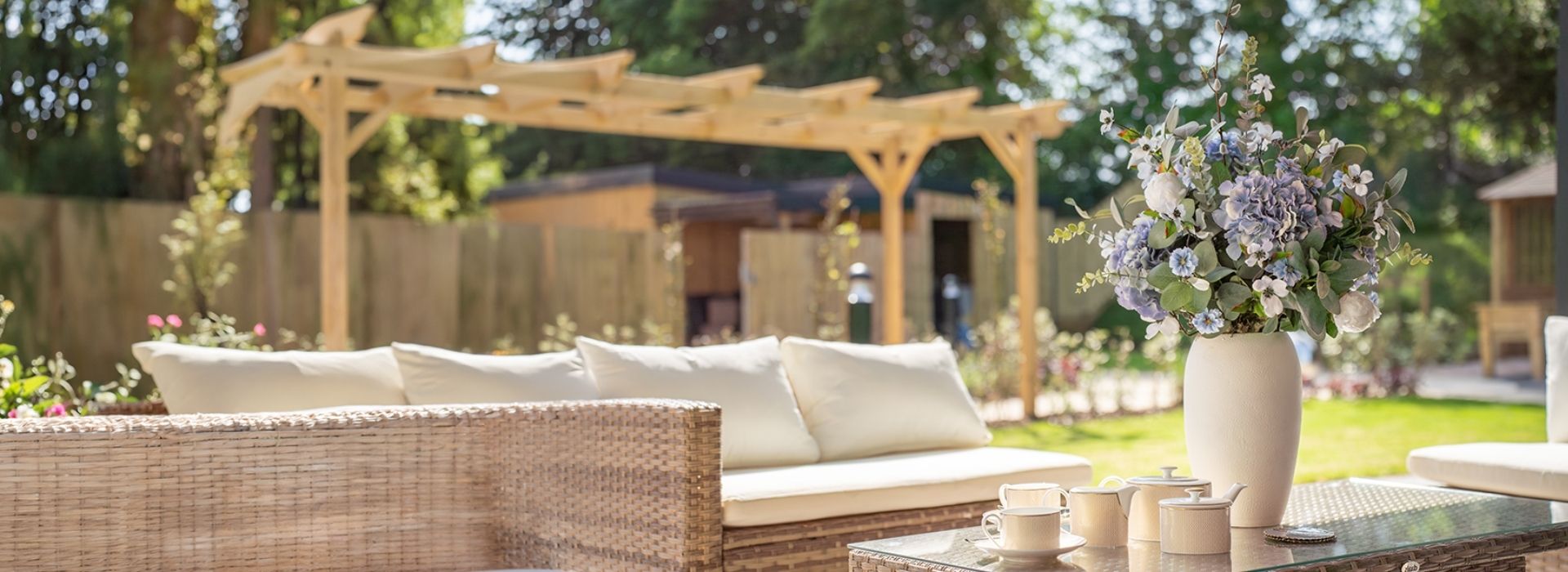 A cozy patio featuring wicker furniture surrounded by vibrant flowers in full bloom.